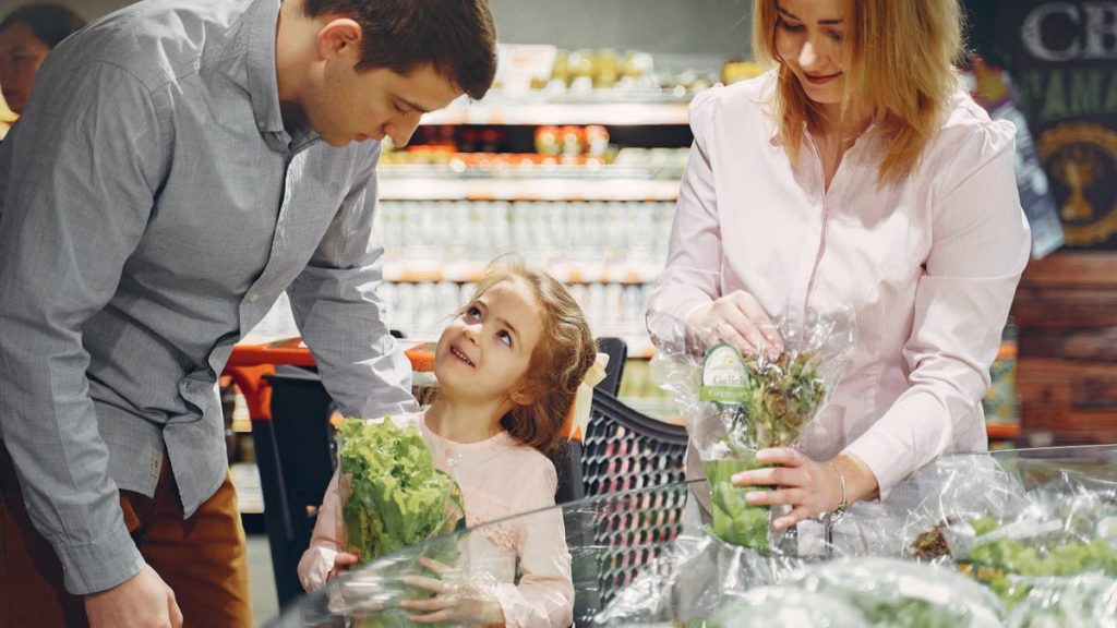 A family enjoys shopping for fresh produce together in a supermarket, smiling and bonding.