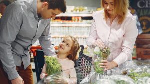 A family enjoys shopping for fresh produce together in a supermarket, smiling and bonding.