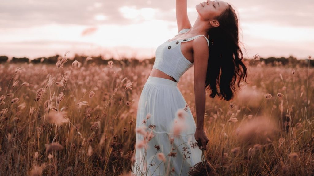 woman in white and red floral dress standing on brown grass field during daytime